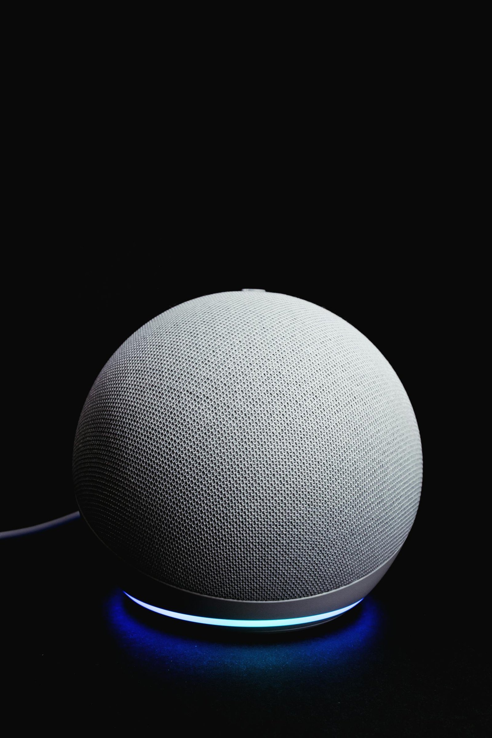 A stylish smart speaker glowing on a dark background, showcasing modern technology.